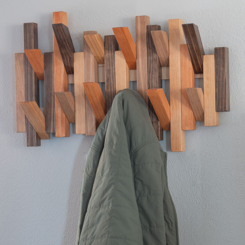 wooden piano coat rack on wall with green jacket